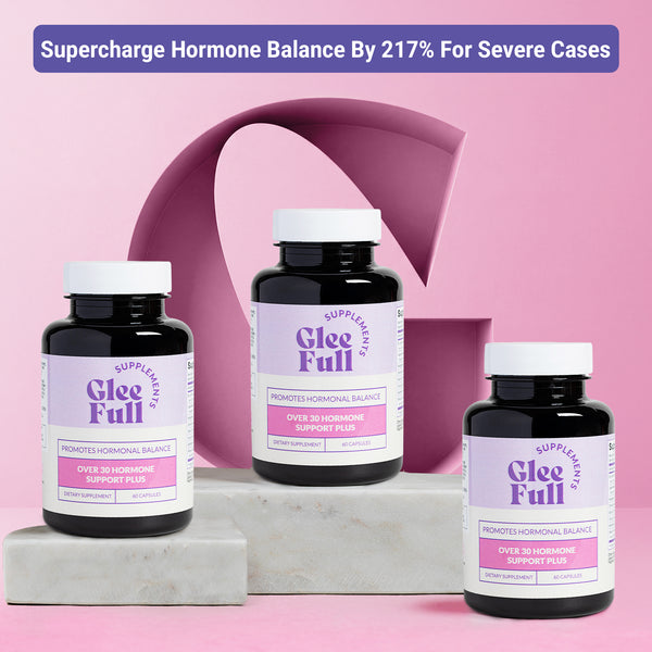 Product display for GleeFull Over 30 Hormone Support Plus dietary supplement. A purple banner across the top reads: 'Supercharge Hormone Balance By 217% For Severe Cases'. Three dark amber bottles with white caps and purple and pink labels are arranged on grey marble blocks against a pink background with a large letter G graphic. Each label reads 'GleeFull Supplements, Promotes Hormonal Balance, Over 30 Hormone Support Plus, Dietary Supplement, 60 Capsules'.