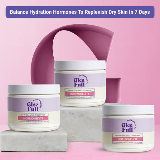 Three white GleeFull Hormonelyte powder jars on marble blocks against a pink background. Purple banner reads: 'Balance Hydration Hormones To Replenish Dry Skin In 7 Days'. Labels read 'Enhances Nutrient Absorption, Hormonelyte, Net Wt. 5.71 oz (162 g)'.