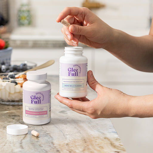GleeFull Over 30 Hormone Support and Meno Belly Flusher bottles on a marble countertop in a kitchen setting.