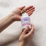 Person holding a Gleefull Over 30 Hormone support bottle with beige capsules on a light background