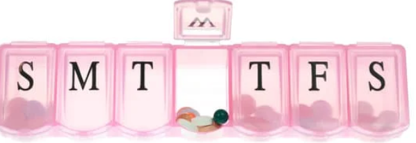 A pink 7-day pill box organizer with compartments labeled S, M, T, W, T, F, S for each day of the week. Some pills are visible in the compartments.